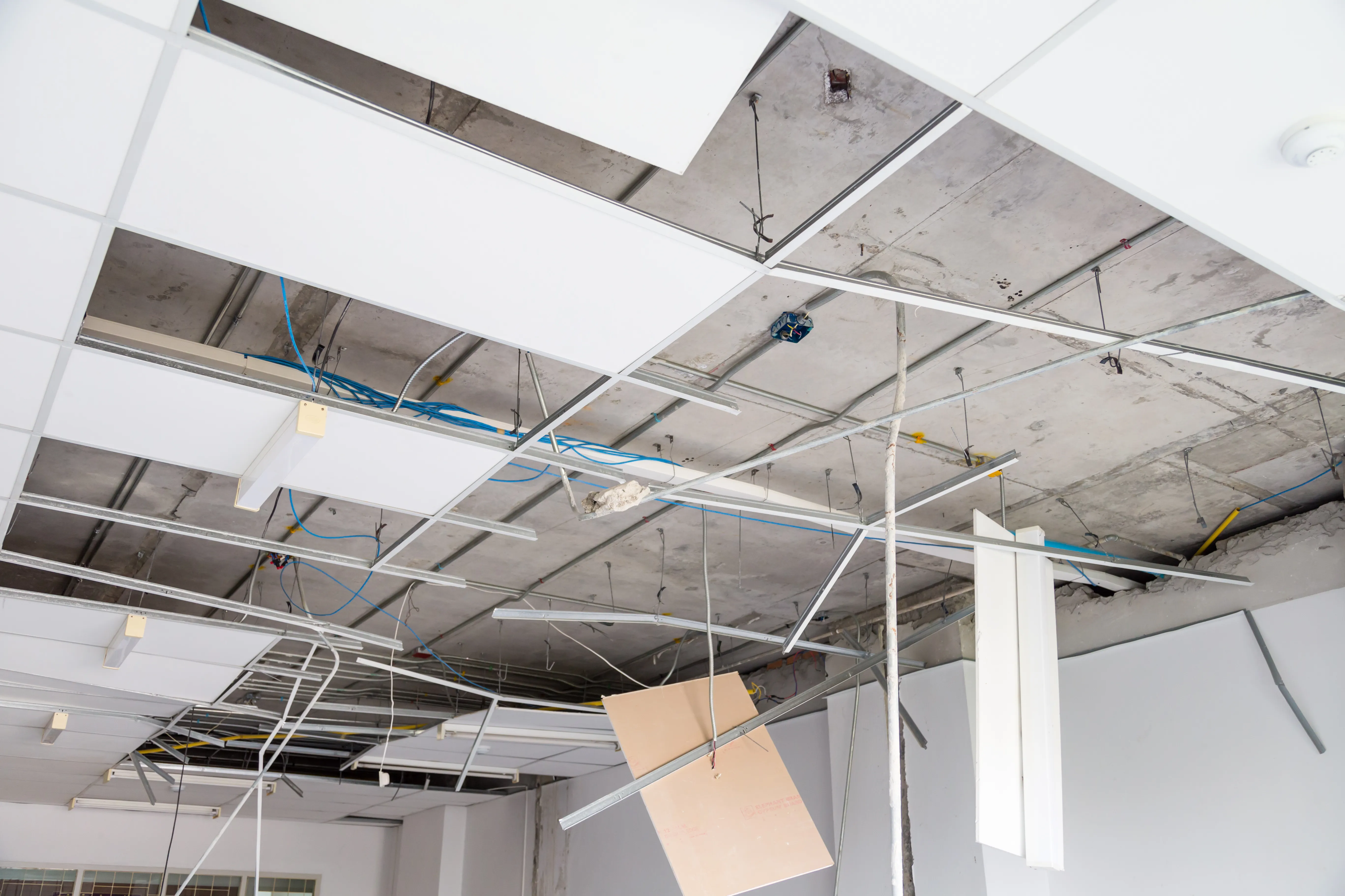 Commercial interior demolition in Dallas TX showing exposed wiring after drop ceiling removal during office renovation