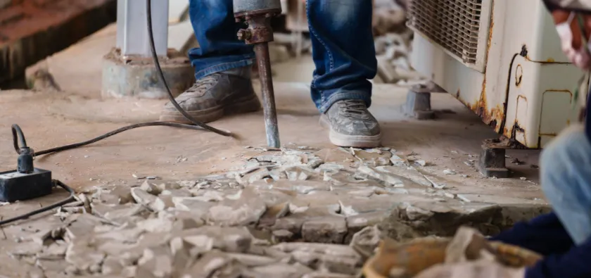 Concrete removal in Dallas TX with jackhammer breaking concrete floor during demolition process