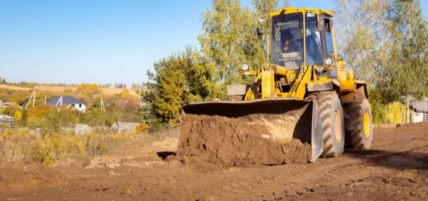 Land clearing in Dallas TX with bulldozer grading soil during site preparation