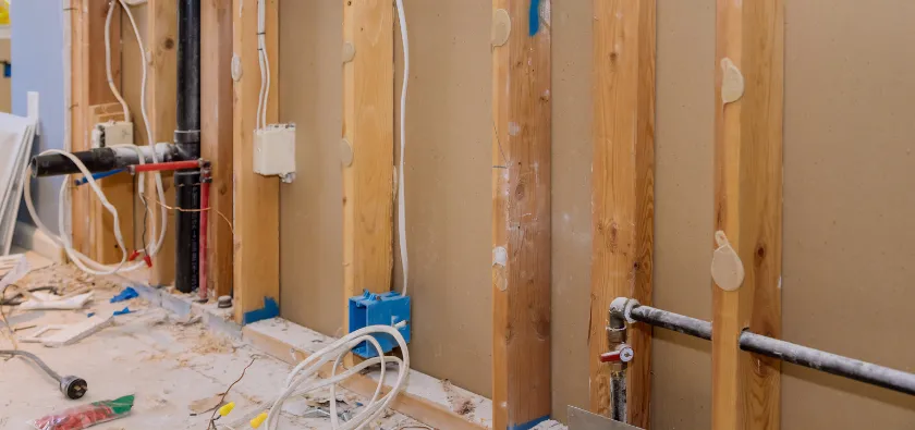 Residential interior demolition in Dallas TX showing exposed wall studs with plumbing and electrical systems during renovation