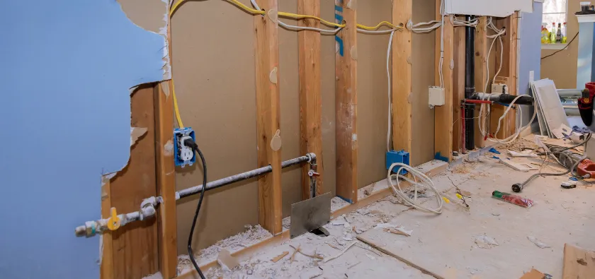 Residential interior demolition in Dallas TX with wall removal exposing framing and debris during home renovation project